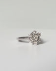 Bague en or gris 18 carats sertie de sept diamants taille brillant en serti griffe formant une fleur sur une monture ajourée, bijou raffiné et lumineux.