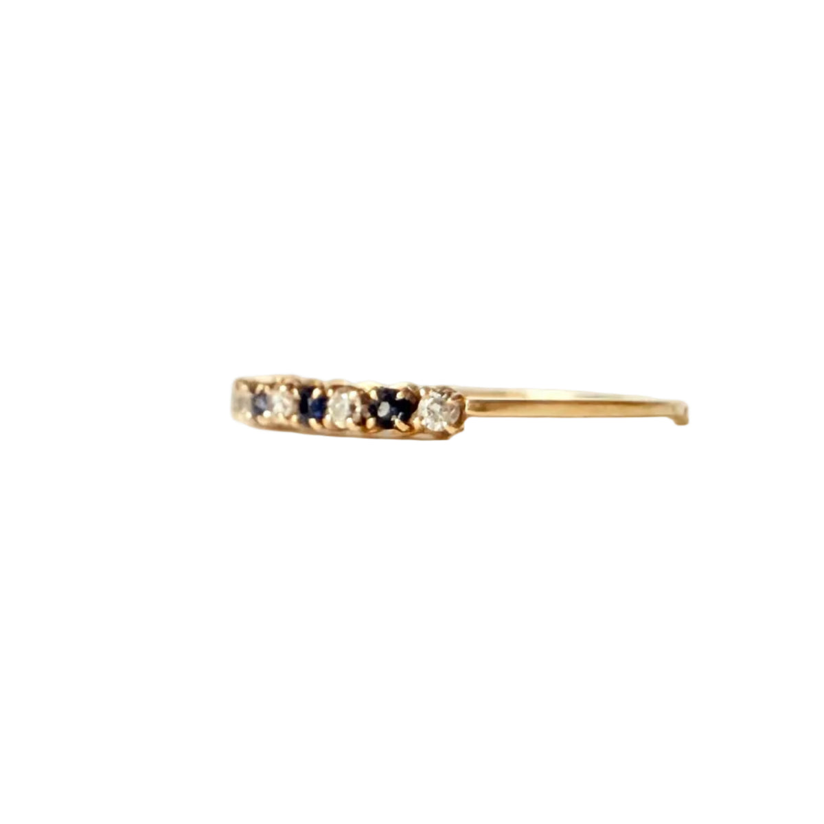 Vue de profil d’une fine bague demi-alliance en or jaune 18 carats sertie de diamants et saphirs