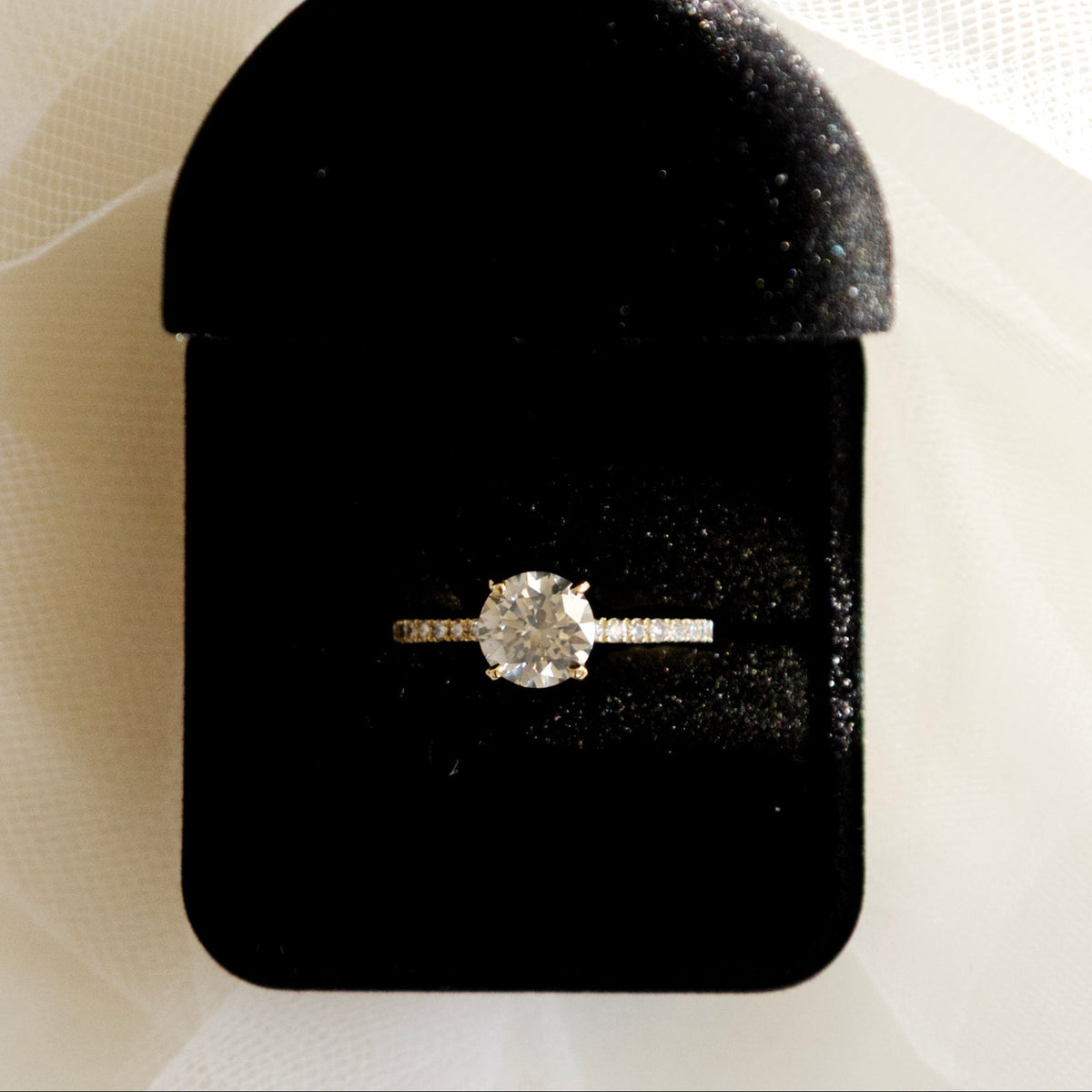 Bague de fiançailles en or jaune ornée d'un important diamant de 1.5 carats sur une monture en or et diamants, dans un écrin. 