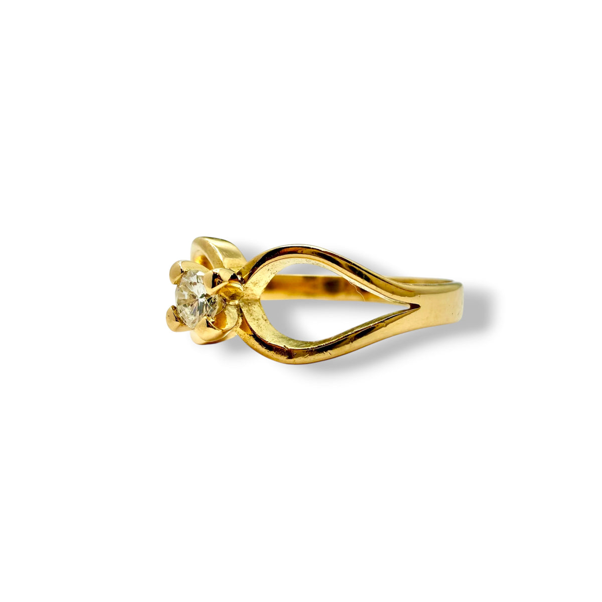 SOlitaire en or jaune 18 carats orné d'un diamant sur une monture en volutes.