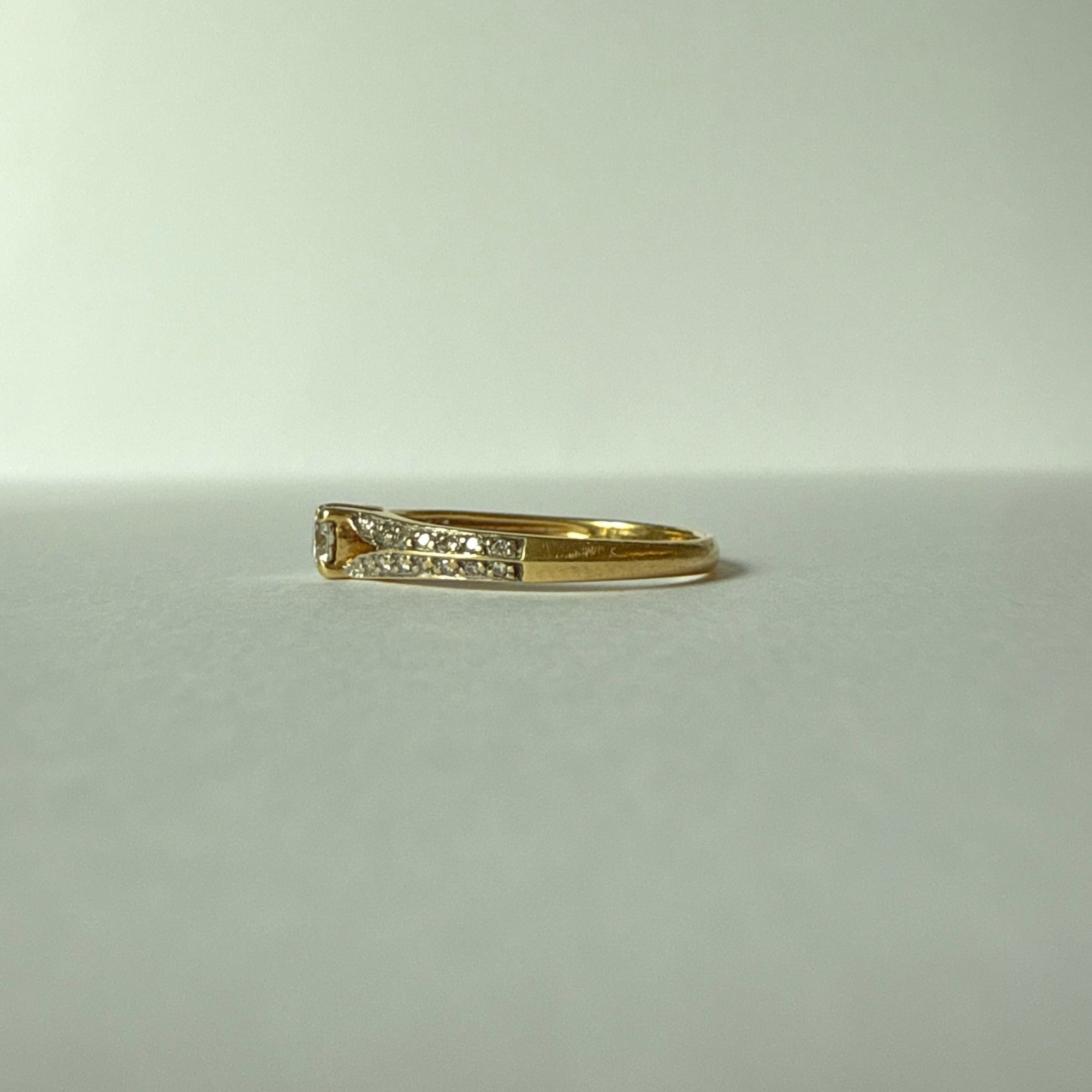 Profil d’une bague solitaire en or jaune 18 carats montrant sa monture ajourée et le sertissage du diamant central.