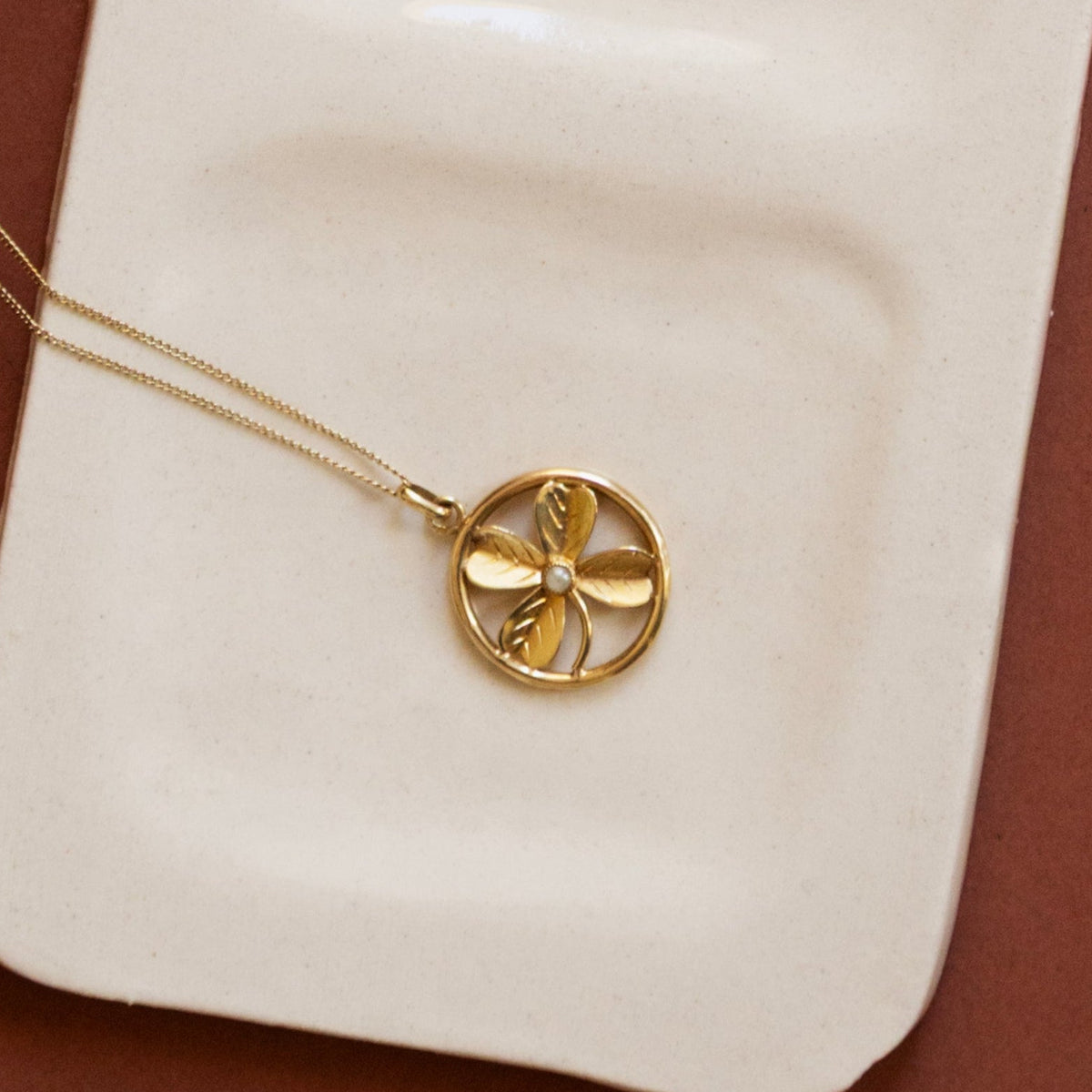 Pendentif ancien en or jaune 18 carats en forme de trèfle à quatre feuilles serti d'une perle de culture, vue de face.